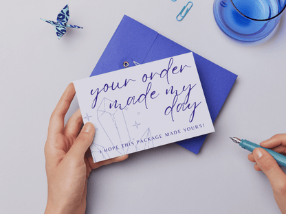 You can see a hand holding an aesthetic and boho your order made my day card template which says "your order made my day, I hope this package made yours!". Perfect for business owners and content creators. It's editable in Canva.